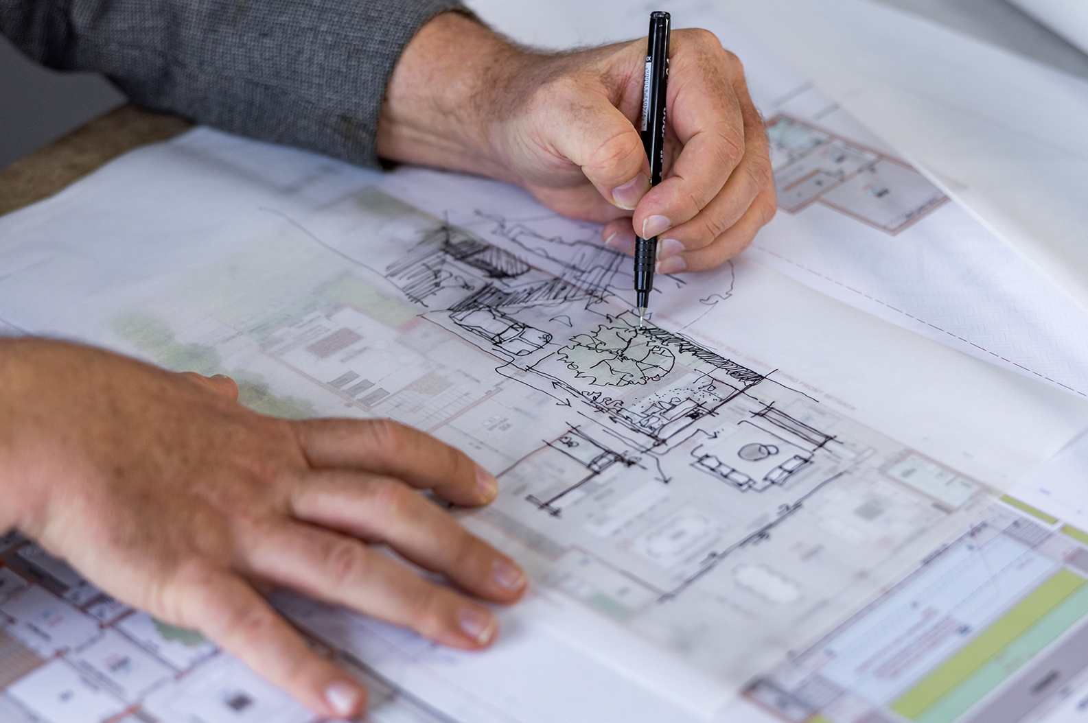Architect drawing on blueprint with pen.