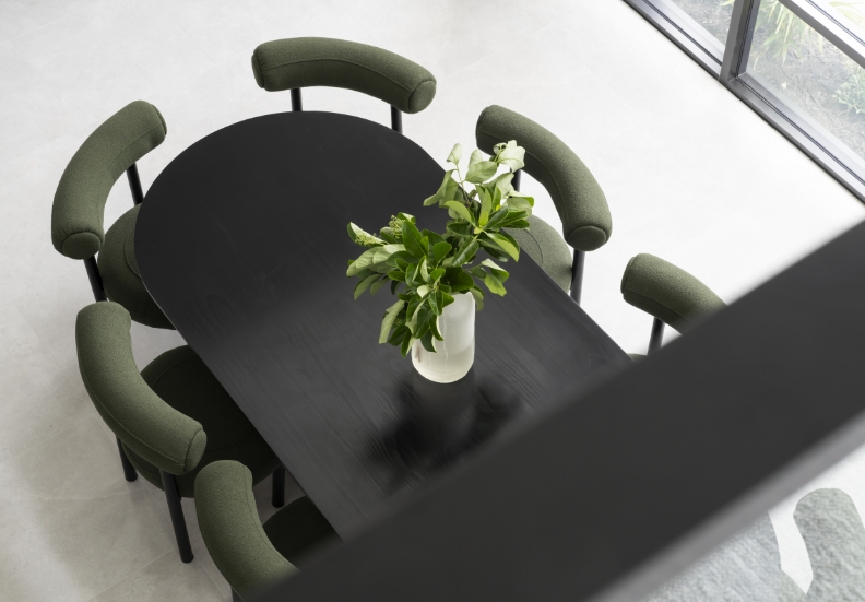 Modern dining room with black table and green chairs.