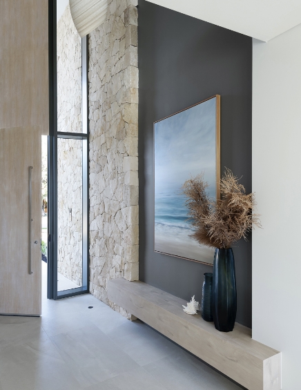 Modern entryway with artwork and natural stone wall.