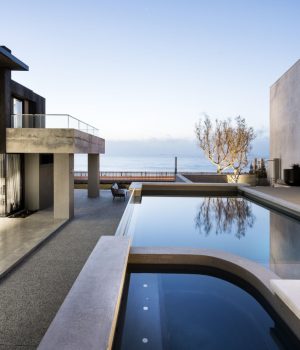Modern seaside villa with infinity pool at dusk.